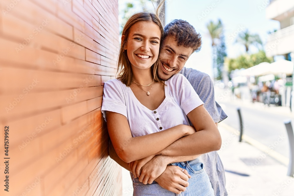 Young hispanic couple smiling happy and hugging standing at the city.