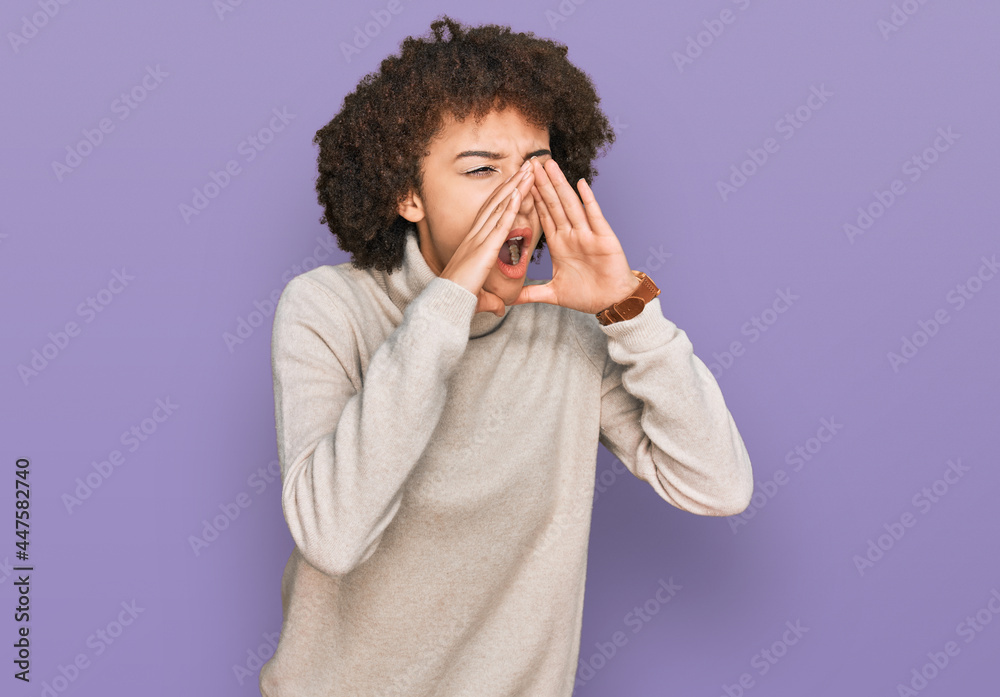 Young hispanic girl wearing wool winter sweater shouting angry out loud with hands over mouth Young hispanic girl wearing wool winter sweater shouting angry out loud with hands over mouth