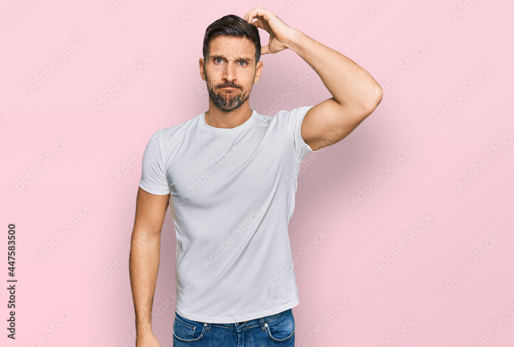 Handsome man with beard wearing casual white t shirt confuse and wonder about question. uncertain with doubt, thinking with hand on head. pensive concept. Handsome man with beard wearing casual white t shirt confuse and wonder about question. uncertain with doubt, thinking with hand on head. pensive concept.