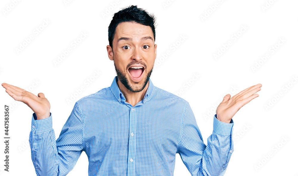 Fototapeta premium Hispanic man with beard wearing casual business shirt celebrating crazy and amazed for success with arms raised and open eyes screaming excited. winner concept