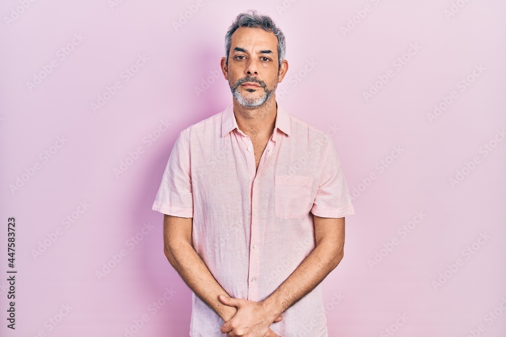 Handsome middle age man with grey hair wearing casual shirt relaxed with serious expression on face. simple and natural looking at the camera. Handsome middle age man with grey hair wearing casual shirt relaxed with serious expression on face. simple and natural looking at the camera.