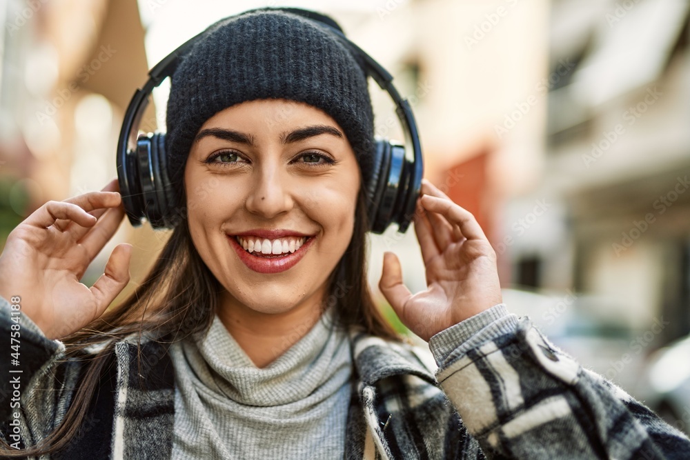 Young hispanic woman smiling happy using headphones at the city. Young hispanic woman smiling happy using headphones at the city.