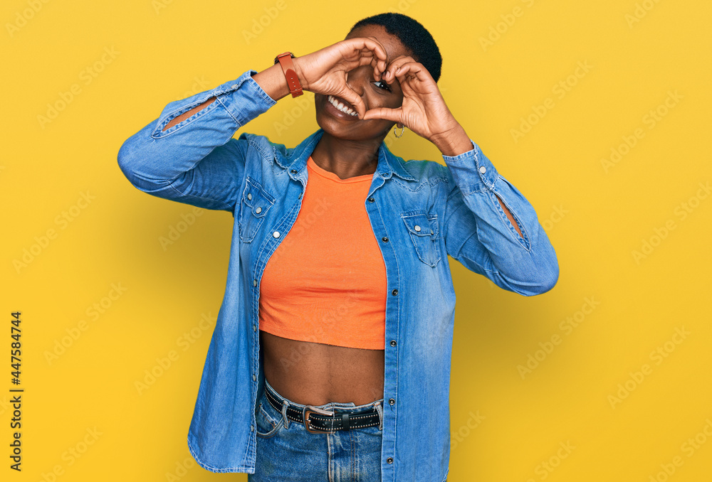 Young african american woman wearing casual clothes doing heart shape with hand and fingers smiling looking through sign Young african american woman wearing casual clothes doing heart shape with hand and fingers smiling looking through sign