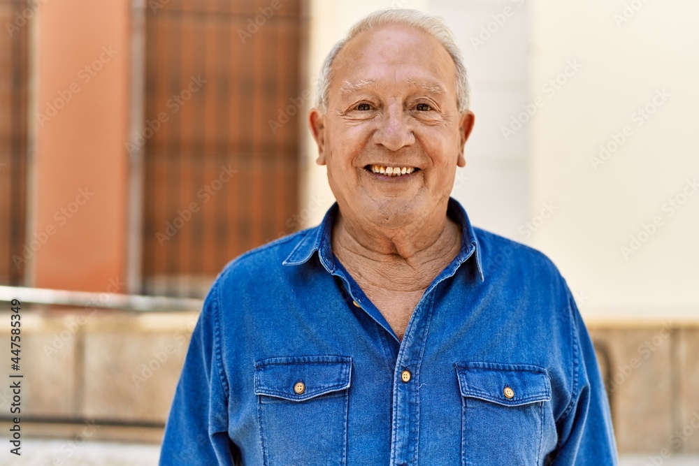 Senior man with grey hair standing happy outdoors on a sunny day. Smiling happy at 70s for retirement.