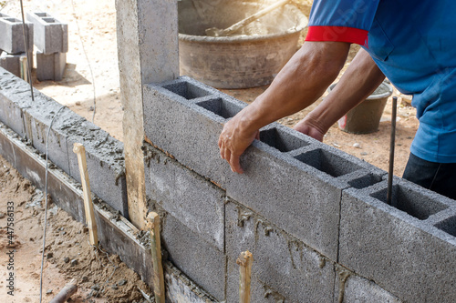 masonry worker make concrete wall by cement block and plaster at construction site photo