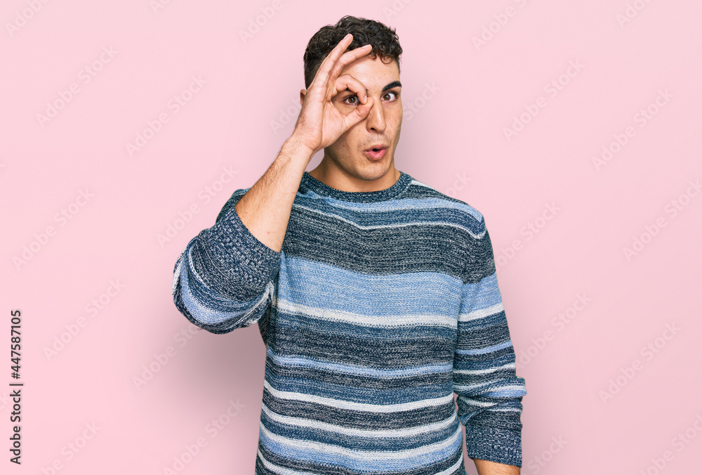 Hispanic young man wearing casual clothes doing ok gesture shocked with surprised face, eye looking through fingers. unbelieving expression. Hispanic young man wearing casual clothes doing ok gesture shocked with surprised face, eye looking through fingers. unbelieving expression.