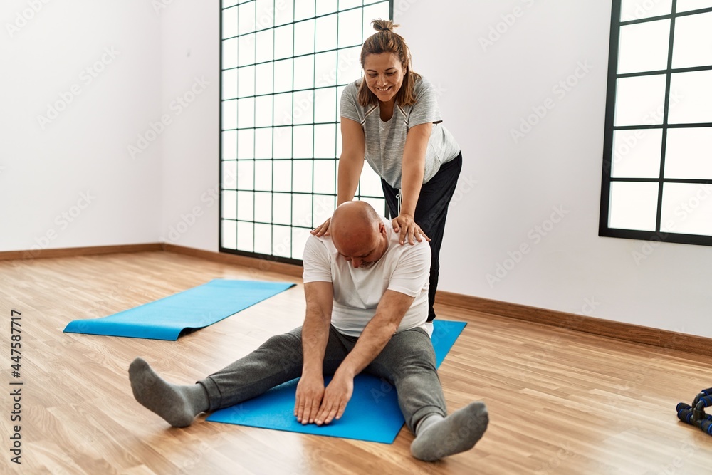 Middle age hispanic couple stretching at sport center. Middle age hispanic couple stretching at sport center.