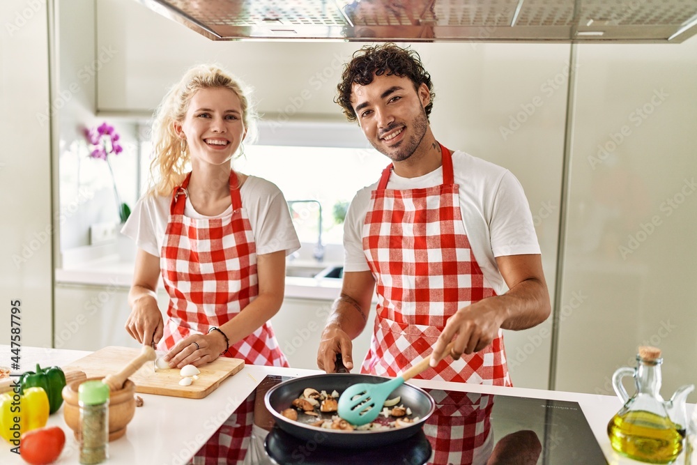 Young couple smiling happy cooking using frying pan at kitchen. Young couple smiling happy cooking using frying pan at kitchen.