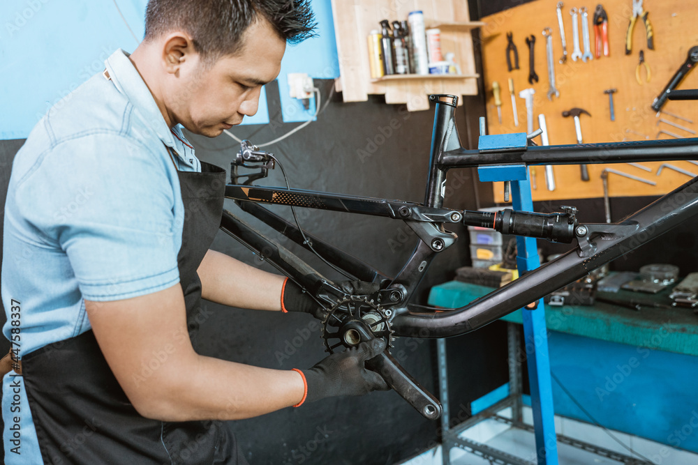 a bicycle mechanic installs a bicycle crank set while assembling a new bicycle in a repair shop
