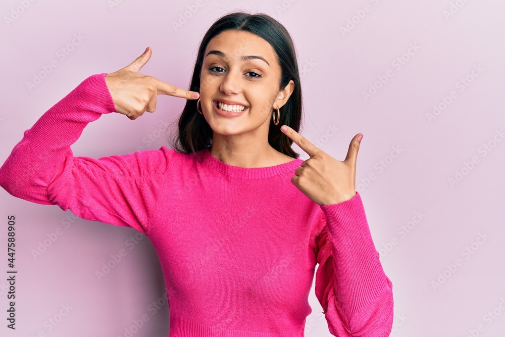 Young hispanic woman wearing casual clothes smiling cheerful showing and pointing with fingers teeth and mouth. dental health concept. Young hispanic woman wearing casual clothes smiling cheerful showing and pointing with fingers teeth and mouth. dental health concept.