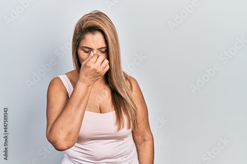 Middle age hispanic woman wearing casual style with sleeveless shirt tired rubbing nose and eyes feeling fatigue and headache. stress and frustration concept.