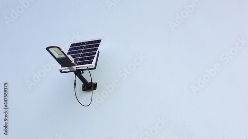 Fototapeta Naklejka Na Ścianę i Meble -  Solar cell light on the wall. A small solar panel mounted on an outdoor building wall with copy space. Selective focus
