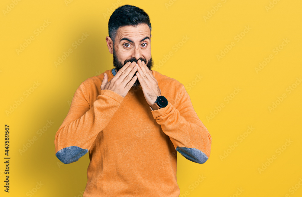 Hispanic man with beard wearing casual winter sweater laughing and embarrassed giggle covering mouth with hands, gossip and scandal concept Hispanic man with beard wearing casual winter sweater laughing and embarrassed giggle covering mouth with hands, gossip and scandal concept