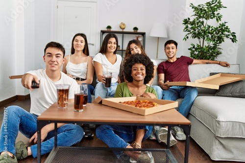 Group of young friends eating italian pizza and watching movie at home.