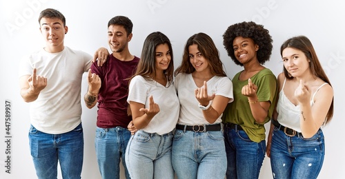 Group of young friends standing together over isolated background beckoning come here gesture with hand inviting welcoming happy and smiling photo
