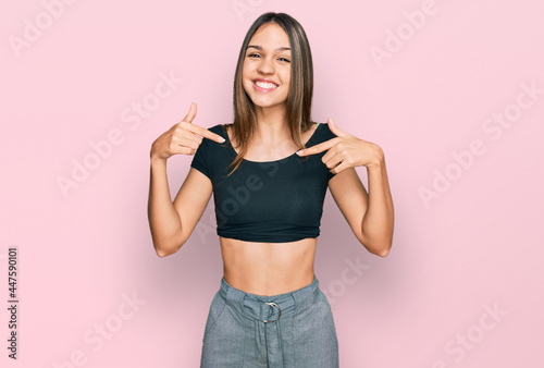 Young brunette woman wearing casual clothes looking confident with smile on face  pointing oneself with fingers proud and happy.
