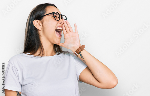 Young hispanic woman wearing casual white t shirt shouting and screaming loud to side with hand on mouth. communication concept.