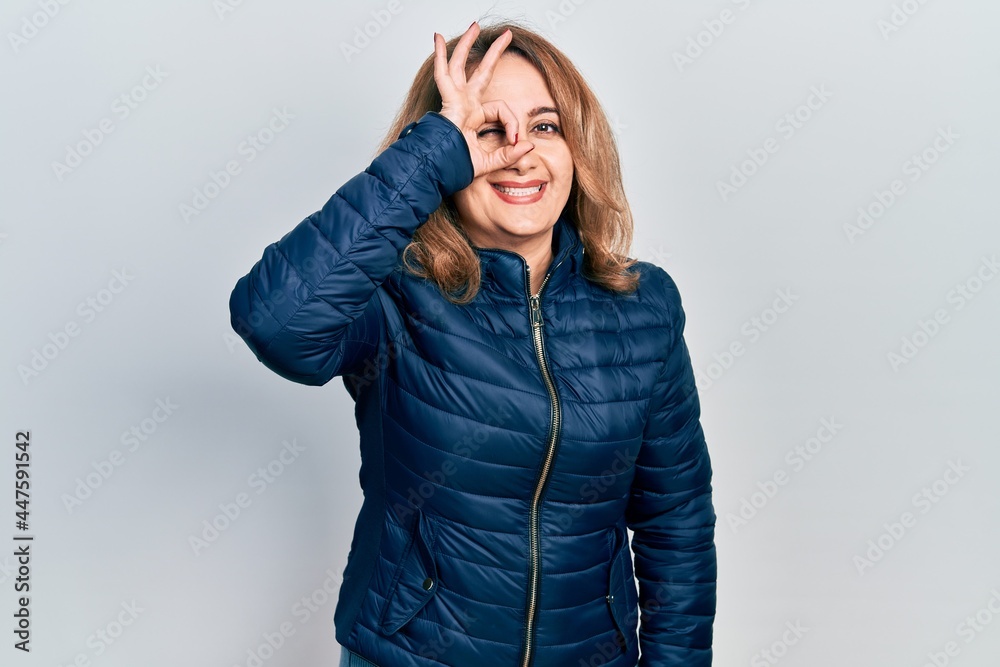 Middle age caucasian woman wearing casual clothes doing ok gesture with hand smiling, eye looking through fingers with happy face.