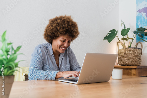 Happy african mature woman using laptop computer at home office - Focus in face photo