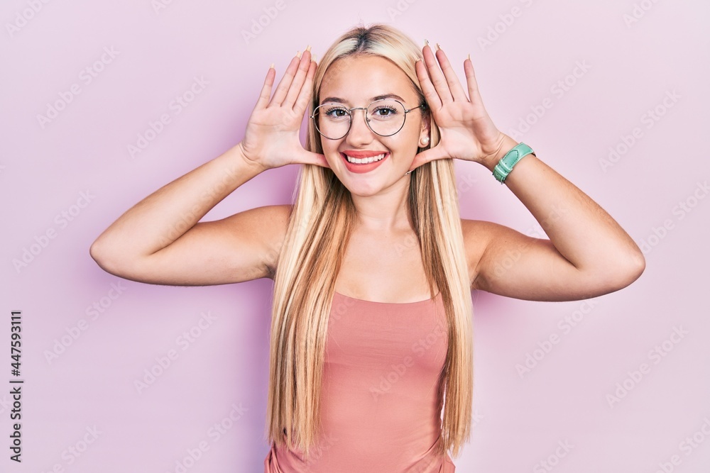Young blonde girl wearing casual clothes smiling cheerful playing peek a boo with hands showing face. surprised and exited Young blonde girl wearing casual clothes smiling cheerful playing peek a boo with hands showing face. surprised and exited