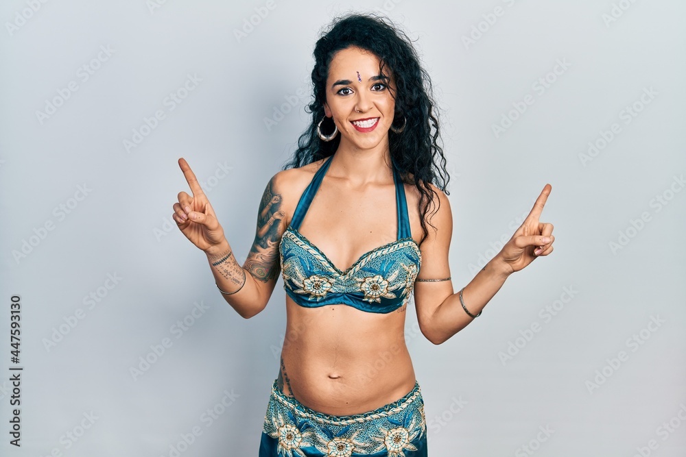 Young woman wearing bindi and traditional belly dance clothes smiling confident pointing with fingers to different directions. copy space for advertisement Young woman wearing bindi and traditional belly dance clothes smiling confident pointing with fingers to different directions. copy space for advertisement