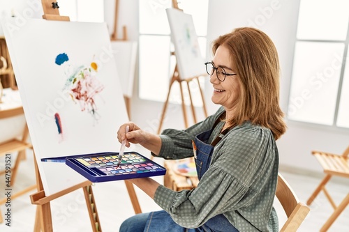 Middle age artist woman smiling happy painting at art studio