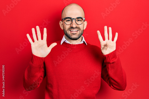 Young bald man wearing casual clothes and glasses showing and pointing up with fingers number nine while smiling confident and happy. © Krakenimages.com