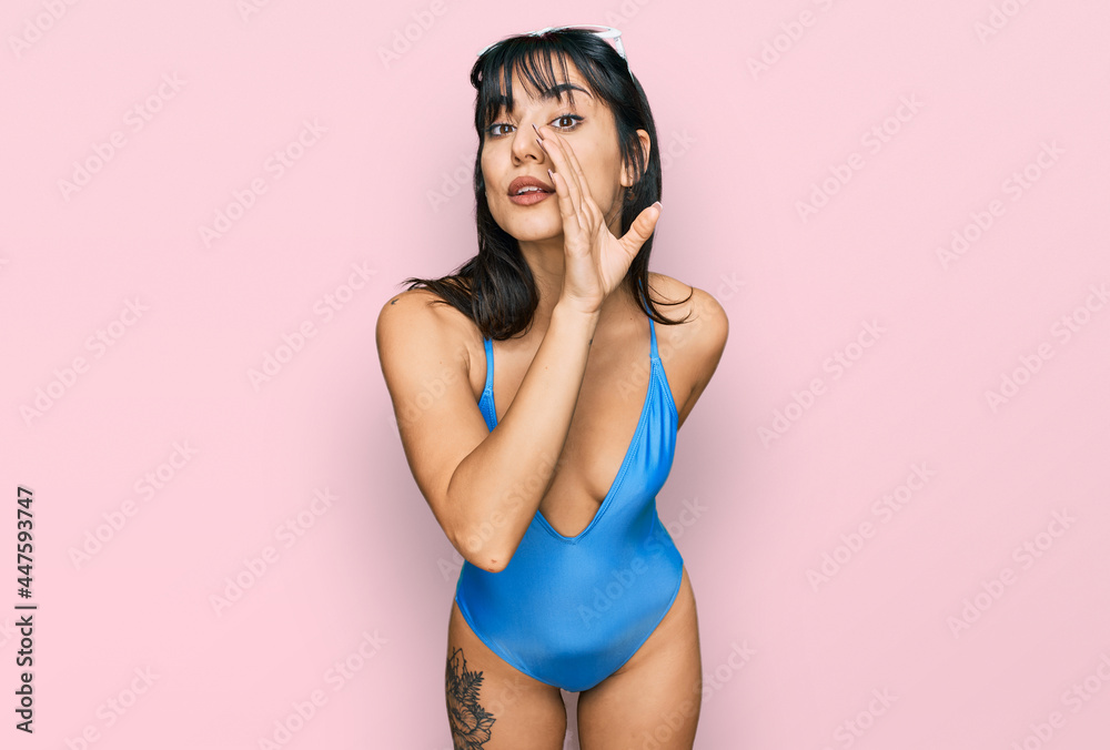 Young hispanic woman wearing swimsuit and sunglasses hand on mouth telling secret rumor, whispering malicious talk conversation Young hispanic woman wearing swimsuit and sunglasses hand on mouth telling secret rumor, whispering malicious talk conversation