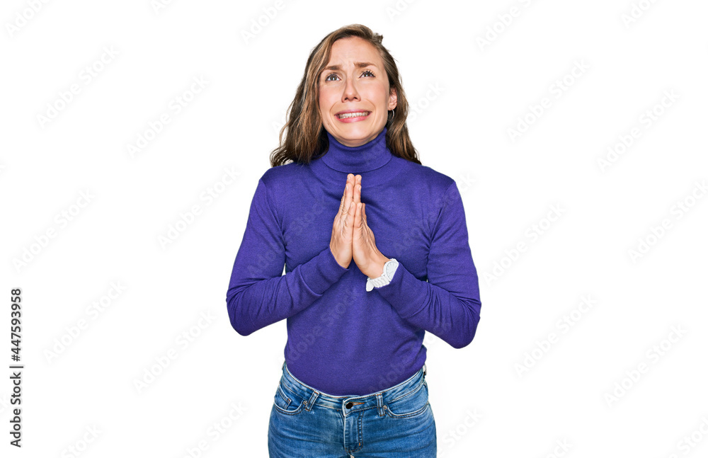 Young blonde woman wearing casual clothes begging and praying with hands together with hope expression on face very emotional and worried. begging.