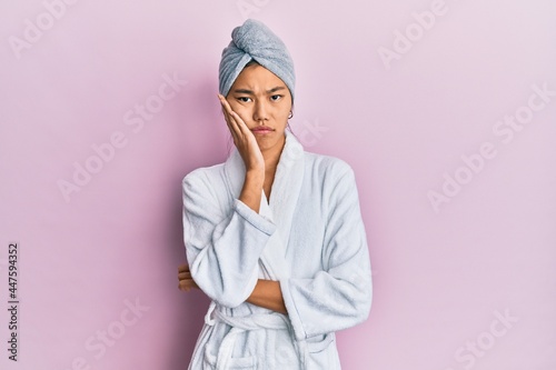 Young chinese woman wearing shower towel cap and bathrobe thinking looking tired and bored with depression problems with crossed arms. photo