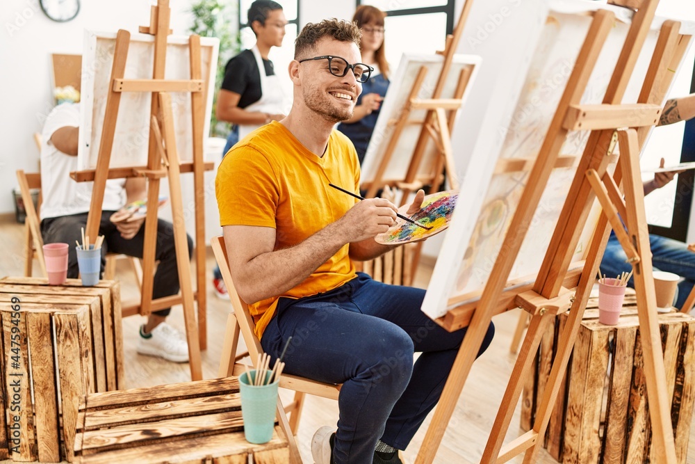 Young man smiling happy drawing with group of people at art studio. Young man smiling happy drawing with group of people at art studio.