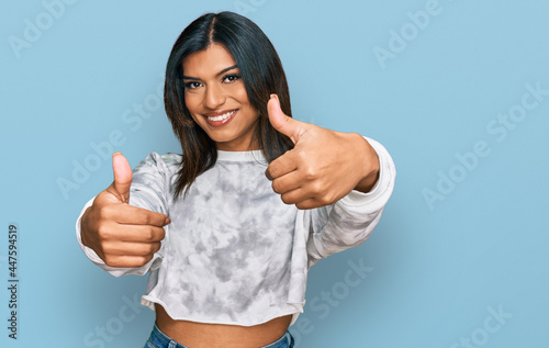 Young latin transsexual transgender woman wearing casual clothes approving doing positive gesture with hand, thumbs up smiling and happy for success. winner gesture.