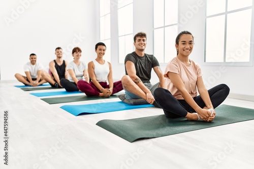 Group of young hispanic people smiling happy training yoga at sport center.