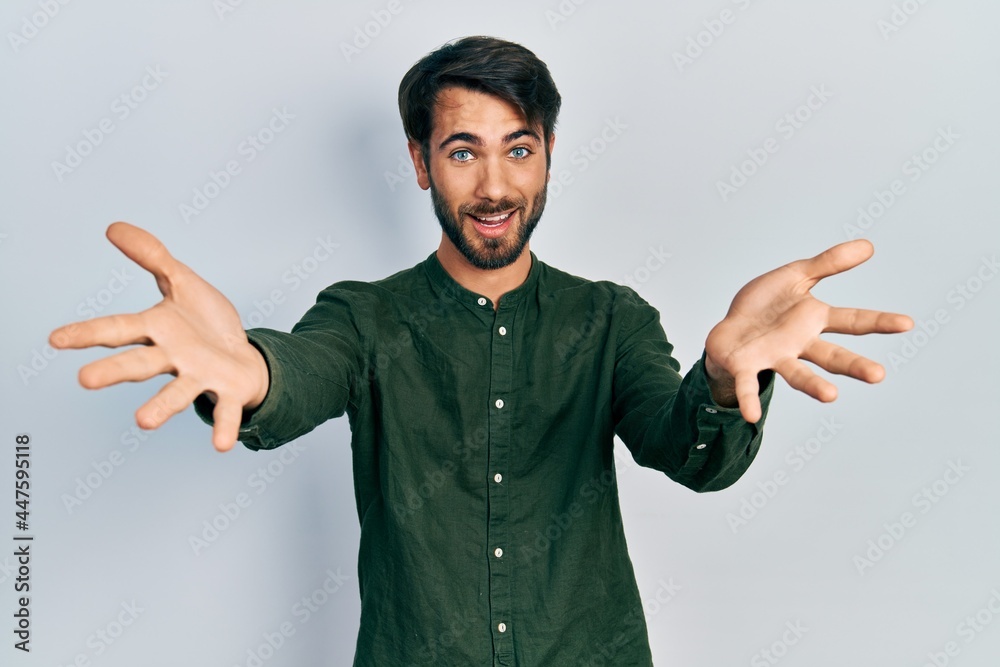 Young hispanic man wearing casual clothes looking at the camera smiling with open arms for hug. cheerful expression embracing happiness. Young hispanic man wearing casual clothes looking at the camera smiling with open arms for hug. cheerful expression embracing happiness.