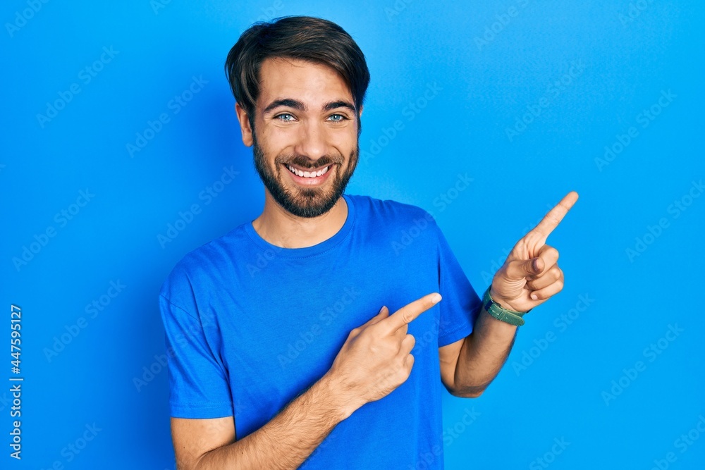 Young hispanic man wearing casual clothes smiling and looking at the camera pointing with two hands and fingers to the side. Young hispanic man wearing casual clothes smiling and looking at the camera pointing with two hands and fingers to the side.