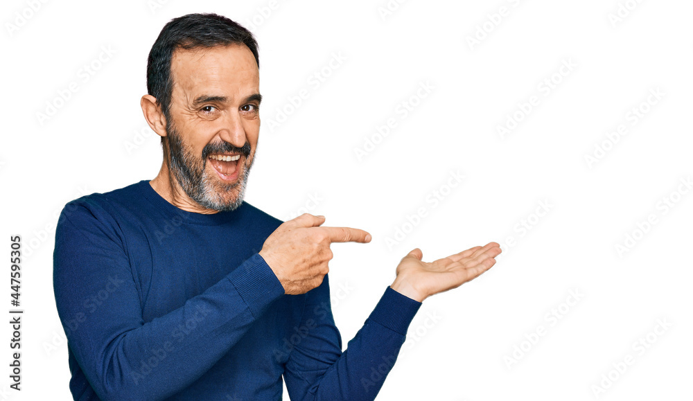 Middle age hispanic man wearing casual clothes amazed and smiling to the camera while presenting with hand and pointing with finger. Middle age hispanic man wearing casual clothes amazed and smiling to the camera while presenting with hand and pointing with finger.