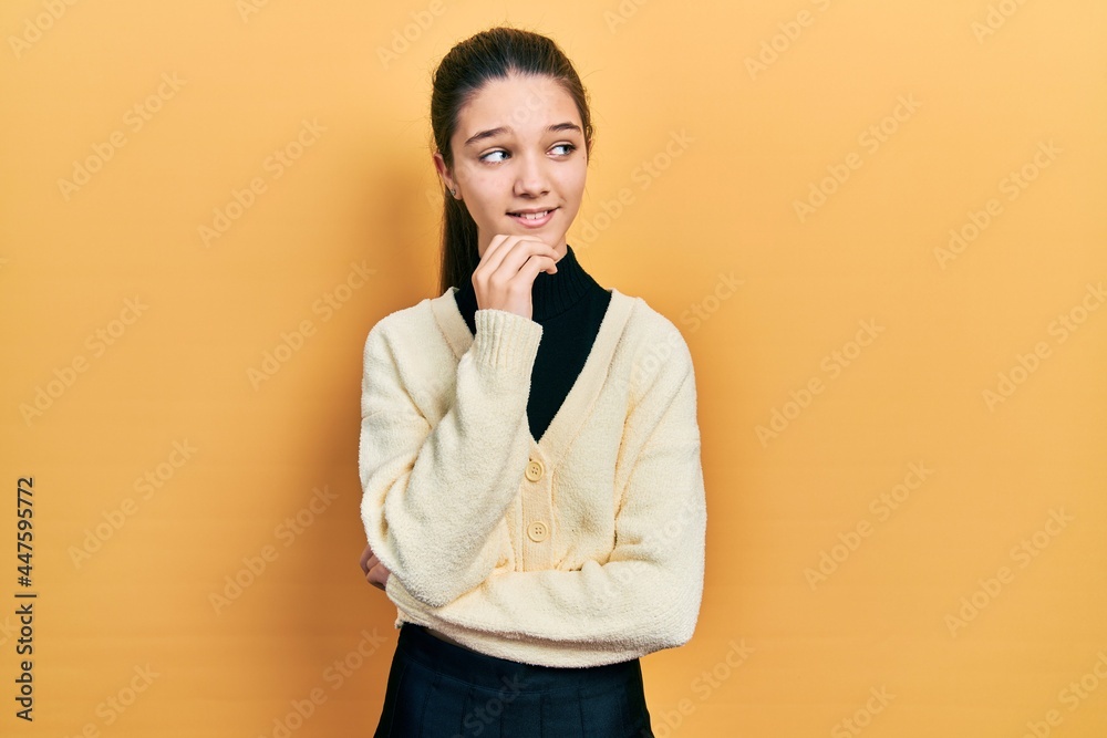 Young brunette girl wearing casual yellow jacket thinking concentrated about doubt with finger on chin and looking up wondering Young brunette girl wearing casual yellow jacket thinking concentrated about doubt with finger on chin and looking up wondering