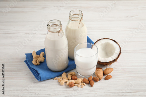 Different nut milks on white wooden table