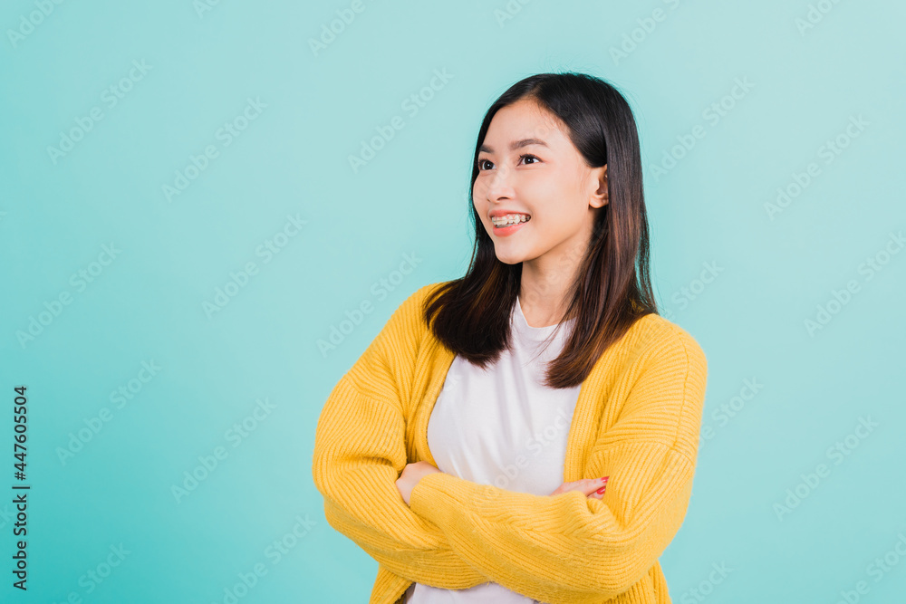 Young Asian beautiful woman smiling wear silicone orthodontic retainers on teeth with crossed arms, studio isolated on blue background, retaining tools after removable braces. Dental hygiene concept Young Asian beautiful woman smiling wear silicone orthodontic retainers on teeth with crossed arms, studio isolated on blue background, retaining tools after removable braces. Dental hygiene concept