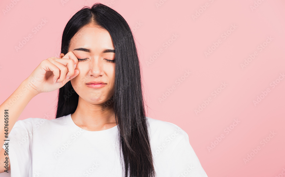 Asian portrait beautiful cute young woman bad mood her cry wipe tears with fingers, studio shot isolated on pink background, Thai female feeling sad unhappy crying with copy space Asian portrait beautiful cute young woman bad mood her cry wipe tears with fingers, studio shot isolated on pink background, Thai female feeling sad unhappy crying with copy space