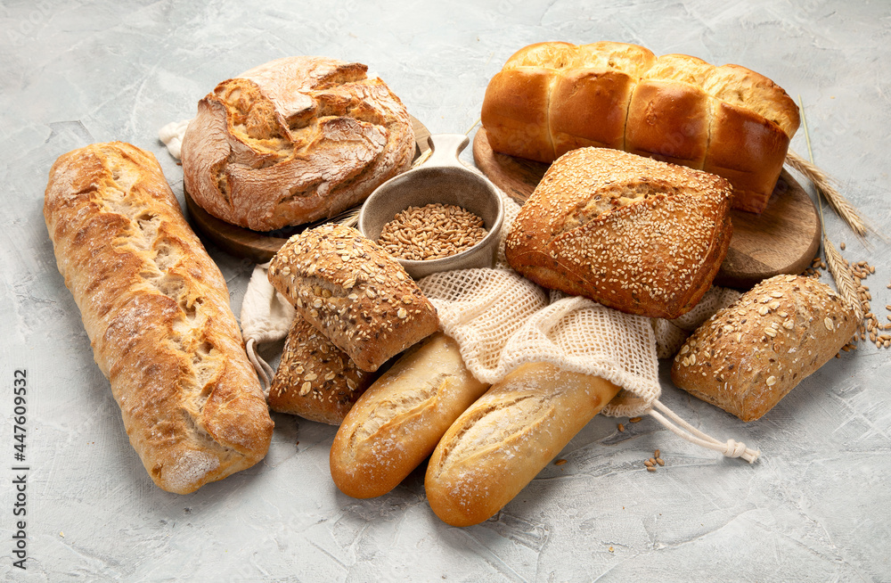 Naklejka premium Various types of fresh baked bread on light gray background.