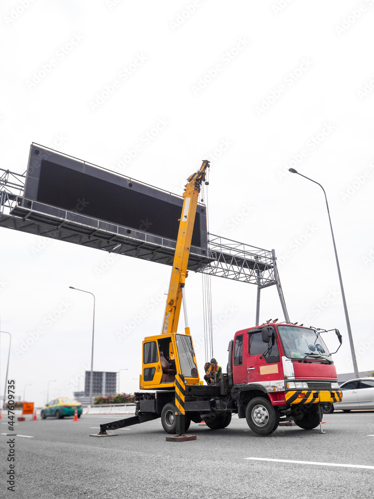 Construction site crane is lifting a led signboard for advertisement