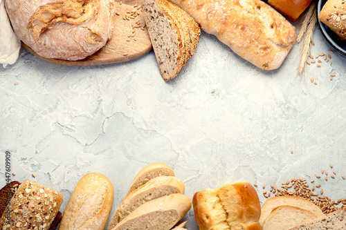 Various types of fresh baked bread on light gray background.