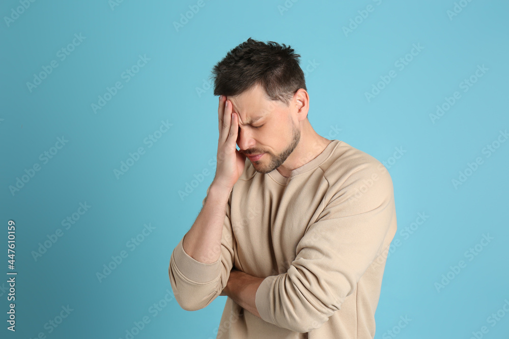 Man suffering from terrible migraine on light blue background Man suffering from terrible migraine on light blue background