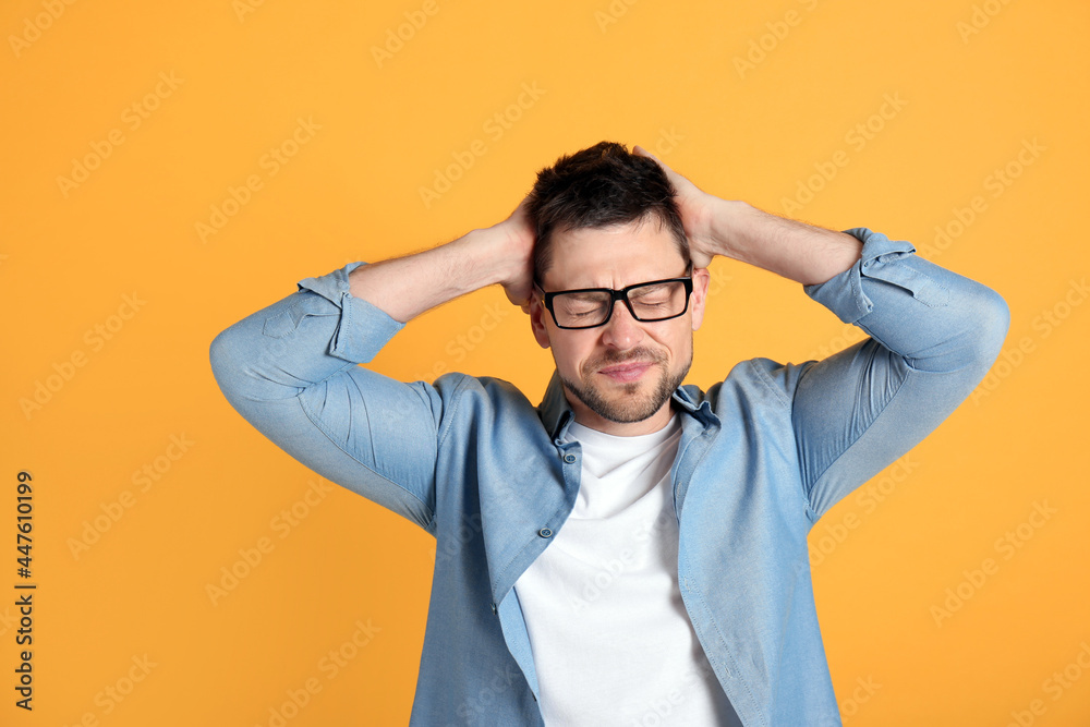 Man suffering from terrible migraine on yellow background Man suffering from terrible migraine on yellow background