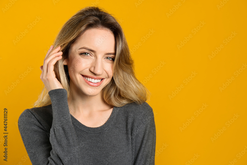 Portrait of happy young woman with beautiful blonde hair and charming smile on yellow background. Space for text Portrait of happy young woman with beautiful blonde hair and charming smile on yellow background. Space for text