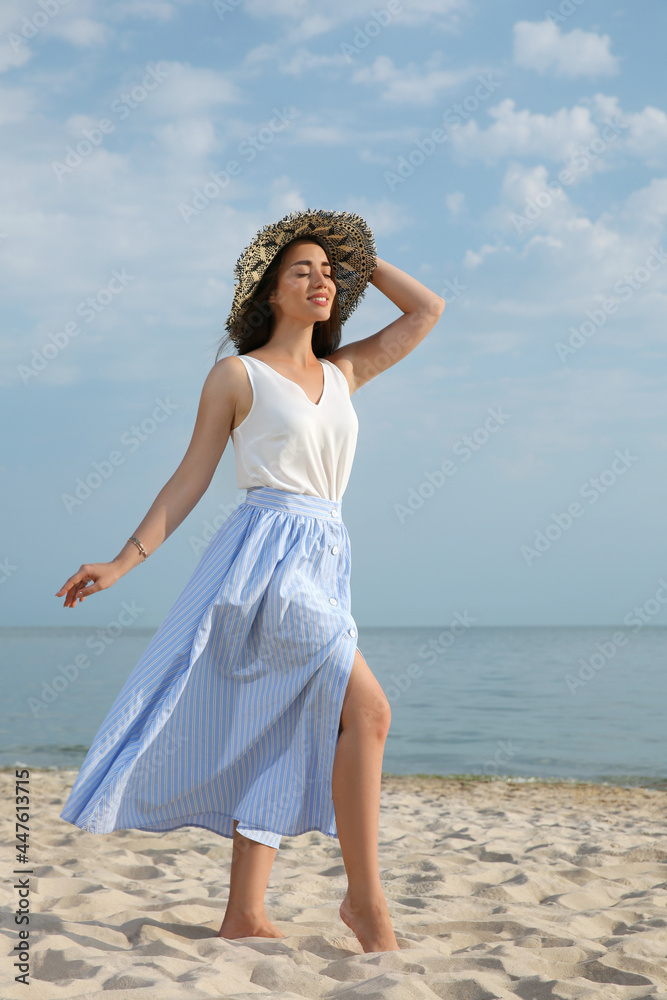 Beautiful young woman wearing straw hat on beach. Stylish headdress Beautiful young woman wearing straw hat on beach. Stylish headdress