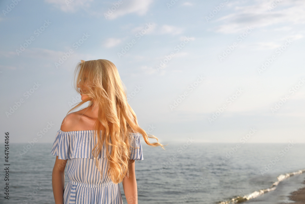 Beautiful young woman near sea on sunny day, space for text