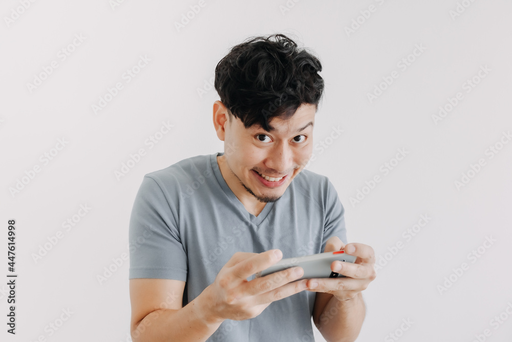 Funny face of Asian man winning the online mobile game isolated on white background. Funny face of Asian man winning the online mobile game isolated on white background.