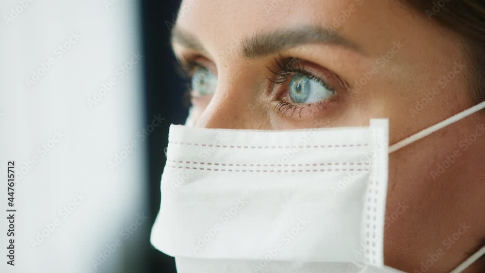 Young woman wearing medical protective face mask close-up, female model with beautiful blue eyes looking in camera side view. Coronavirus self-isolation lockdown concept. Young woman wearing medical protective face mask close-up, female model with beautiful blue eyes looking in camera side view. Coronavirus self-isolation lockdown concept.
